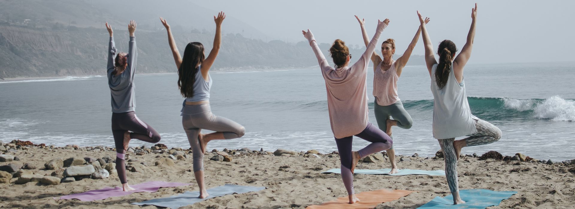 Programm Listing Category Bridal Yoga Frauengruppe am Strand beim Yoga auf bunten Matten
